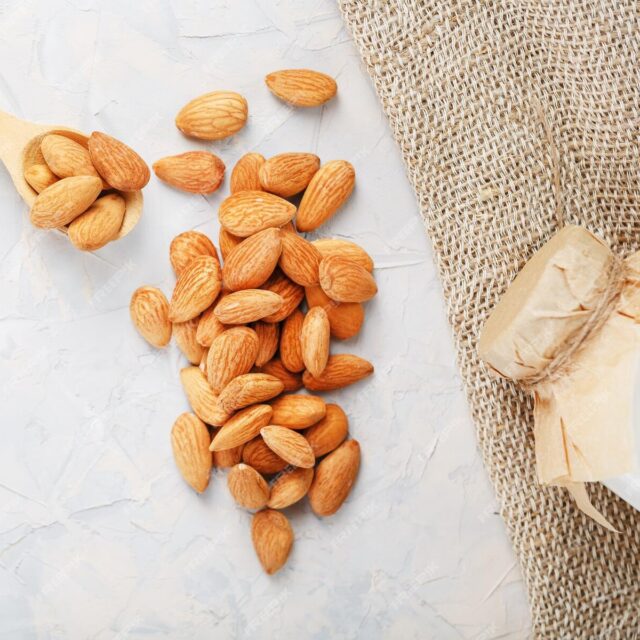 almond-milk-bottle-with-handful-grains-wooden-spoon-with-burlap-cloth-light-background-top-view_94046-8972